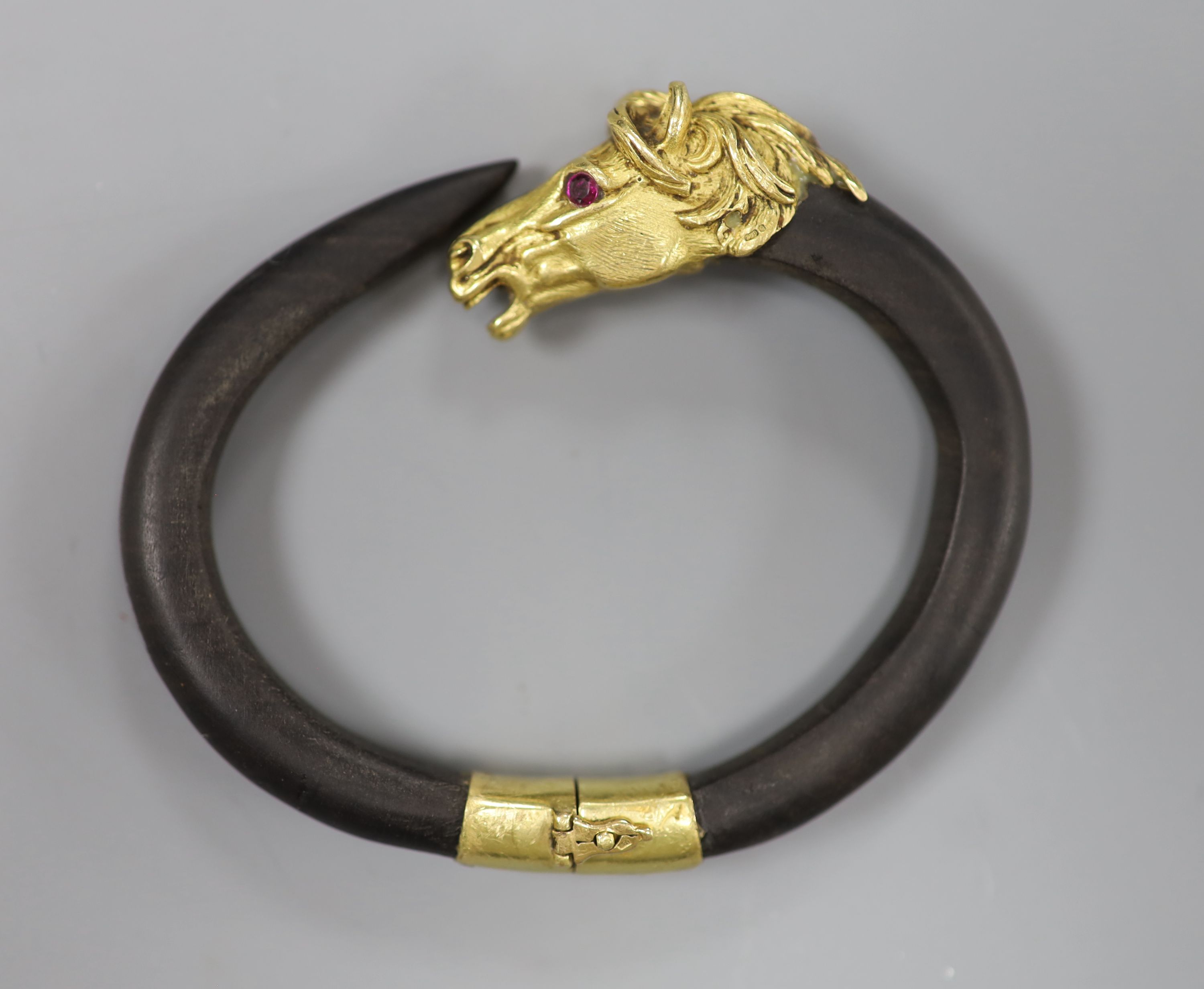 A continental yellow metal and gem set mounted wooden? bangle, with horse head terminal, gross 40 grams,